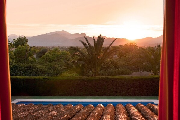 Vista a la piscina con montañas al fondo y cielo despejado.