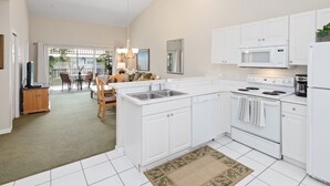 A modern kitchen with white cabinets, a central island, a microwave, and a stove. - Lely Greenlinks 2nd Floor - on Golf Course, Minutes from Beaches, Downtown! (Naples)