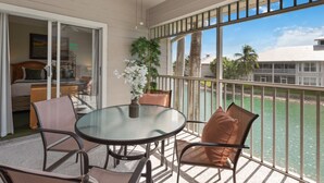 A balcony with a glass table and chairs, a potted plant, and a view of the ocean. - Lely Greenlinks 2nd Floor - on Golf Course, Minutes from Beaches, Downtown! (Naples)