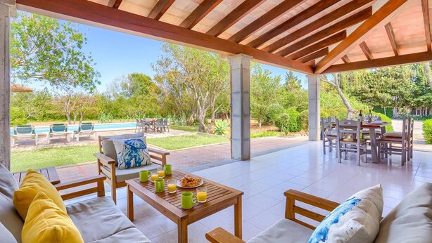 A covered outdoor patio with seating, a pool, and a dining area. - Villa Mari Pollensa by Villa Plus (Mallorca)