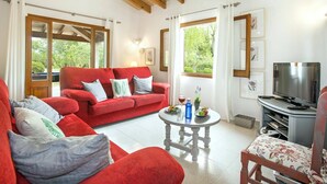 A cozy living room with a red sofa, a wooden coffee table, and a TV stand. - Villa Mari Pollensa by Villa Plus (Mallorca)