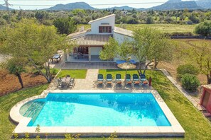 A house with a swimming pool, outdoor seating, and a view of the surrounding landscape.