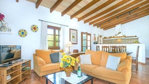 A living room with a sofa, coffee table, TV, and a dining area with chairs and a table.