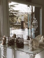 Una vitrina de vidrio con objetos decorativos, un cartel que dice "CAROL Espacio Serrano" y una vista de un parque con una estatua y árboles.
