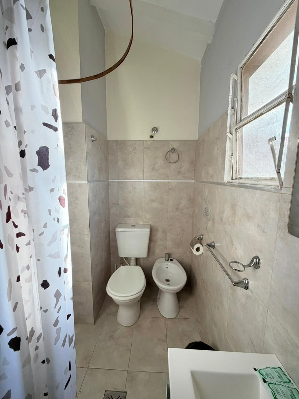 Baño con inodoro, bidé y ventana.