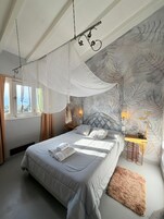 Un dormitorio con cama a dosel, un ventanal grande y una pared con diseño de hojas.