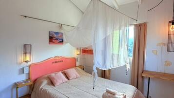 Un dormitorio con cama, dosel, mesita de noche, lámpara y un cuadro en la pared.