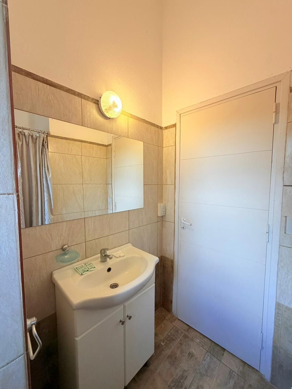 Une salle de bain équipée d’un lavabo, d’un miroir et d’un luminaire.
