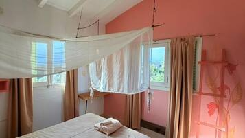 Un dormitorio con cama, cortinas, ventana y una pared decorada con motivos florales.