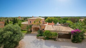 Eine mediterrane Villa mit Ziegeldach, Steinaußenwand und einer Auffahrt, die zu einer Garage führt.