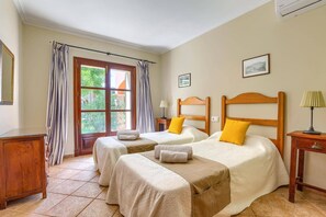 A hotel room with two beds, a window with curtains, a bedside table with a lamp, and a framed picture on the wall. - Villa Marino by Villa Plus (Santañy)