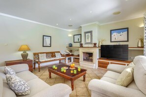 A living room with a sofa set, a coffee table with breakfast items, a fireplace, and a television. - Villa Marino by Villa Plus (Santañy)