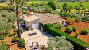 Une maison en pierre avec un toit de tuiles, entourée de jardins bien entretenus et offrant une vue sur la campagne.