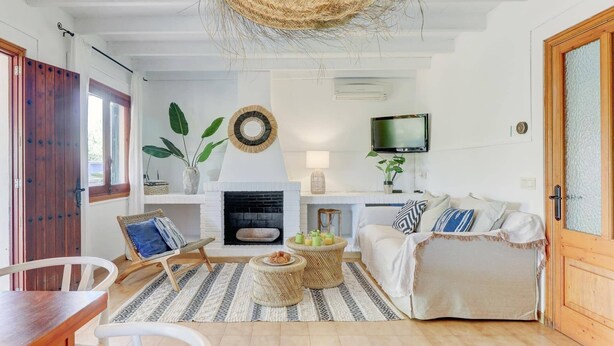 Un salon chaleureux avec une cheminée, un téléviseur fixé au mur et un coin salon confortable avec un canapé et des fauteuils.