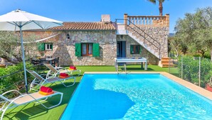 Une villa avec piscine, des murs en pierre et un balcon.