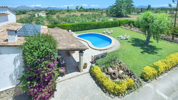 A residential property with a swimming pool, a patio with seating, and a view of the surrounding landscape.
