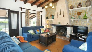 A cozy living room with a blue sofa set, a fireplace, and decorative pottery on shelves.