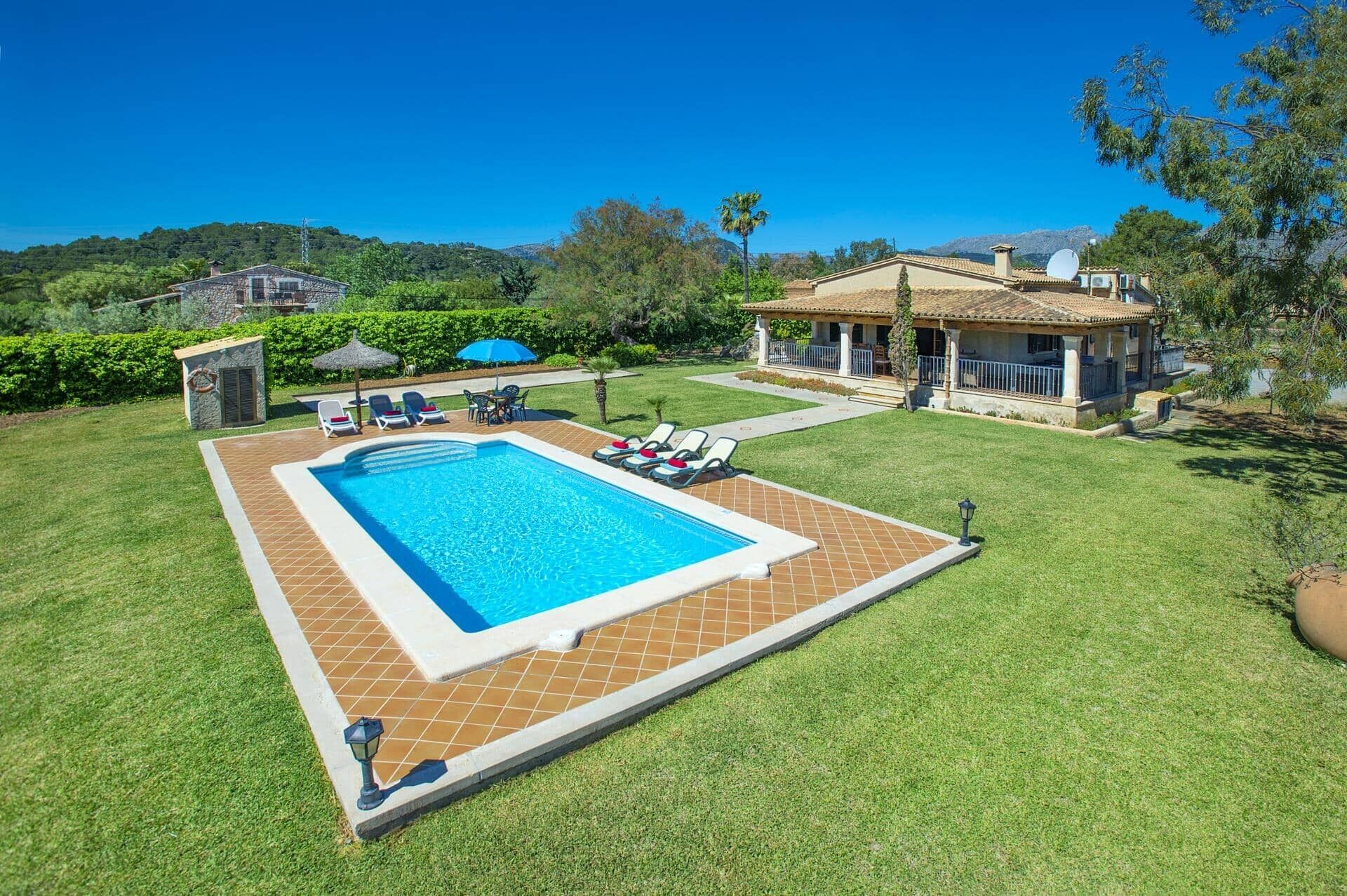 Una piscina con lettini, una piccola struttura a bordo piscina e una casa con patio.