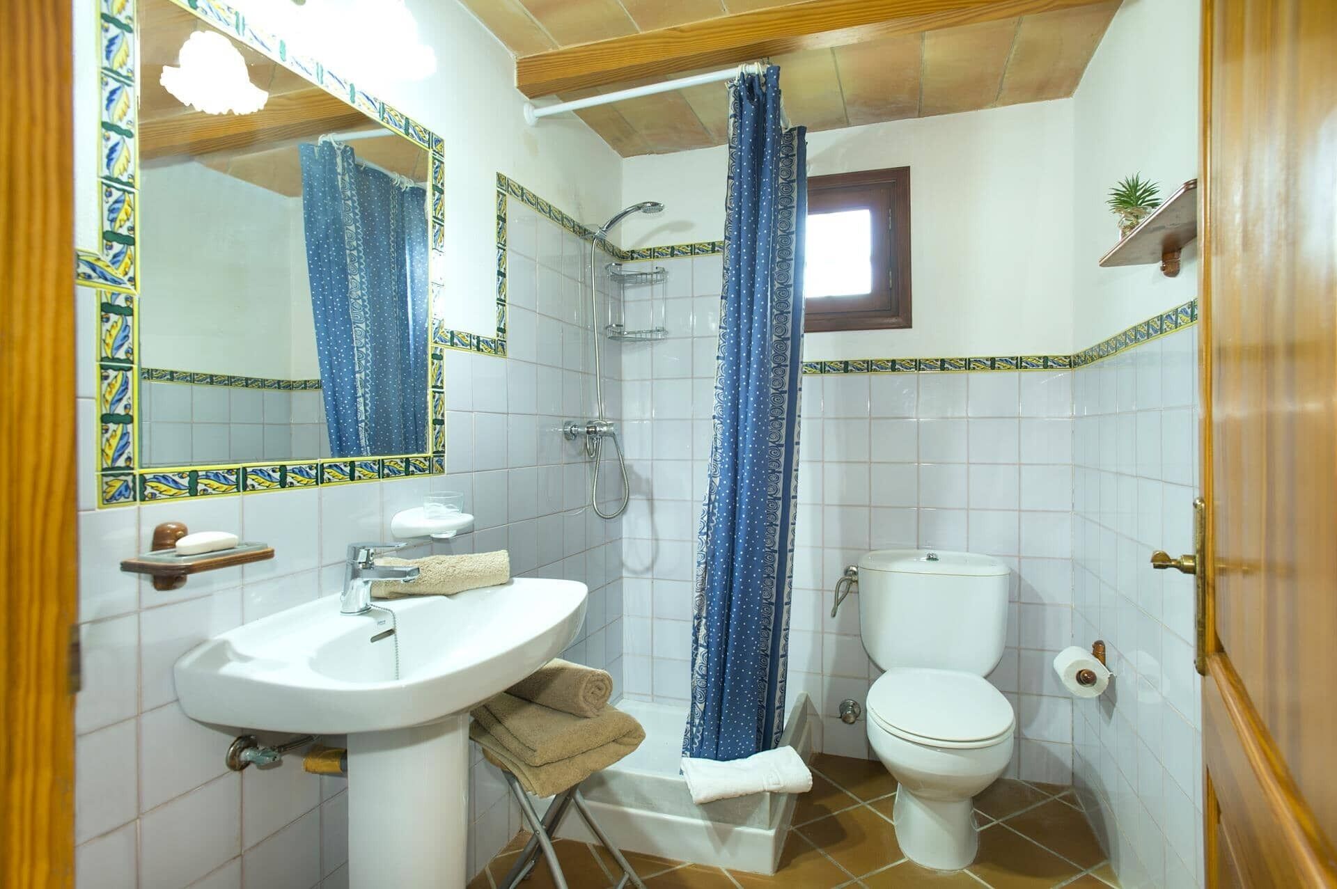 A bathroom with a sink, toilet, shower, and a mirror.