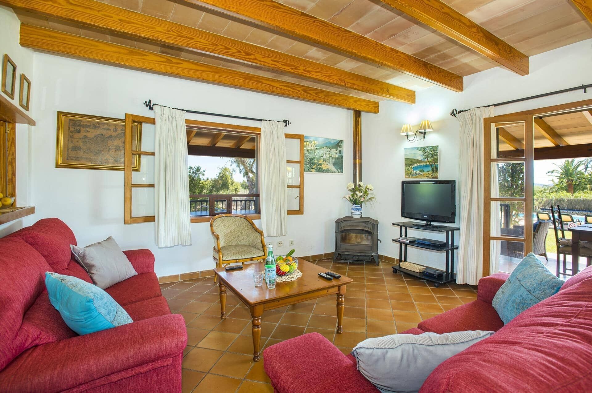 A living room with red sofas, a wooden coffee table, a TV, and a fireplace.