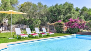 A swimming pool with four lounge chairs and a sun umbrella. - Villa Olivo by Villa Plus (Mallorca)