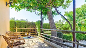 A covered outdoor seating area with wicker chairs and a table, a bottle of wine, and a book. - Villa Olivo by Villa Plus (Mallorca)