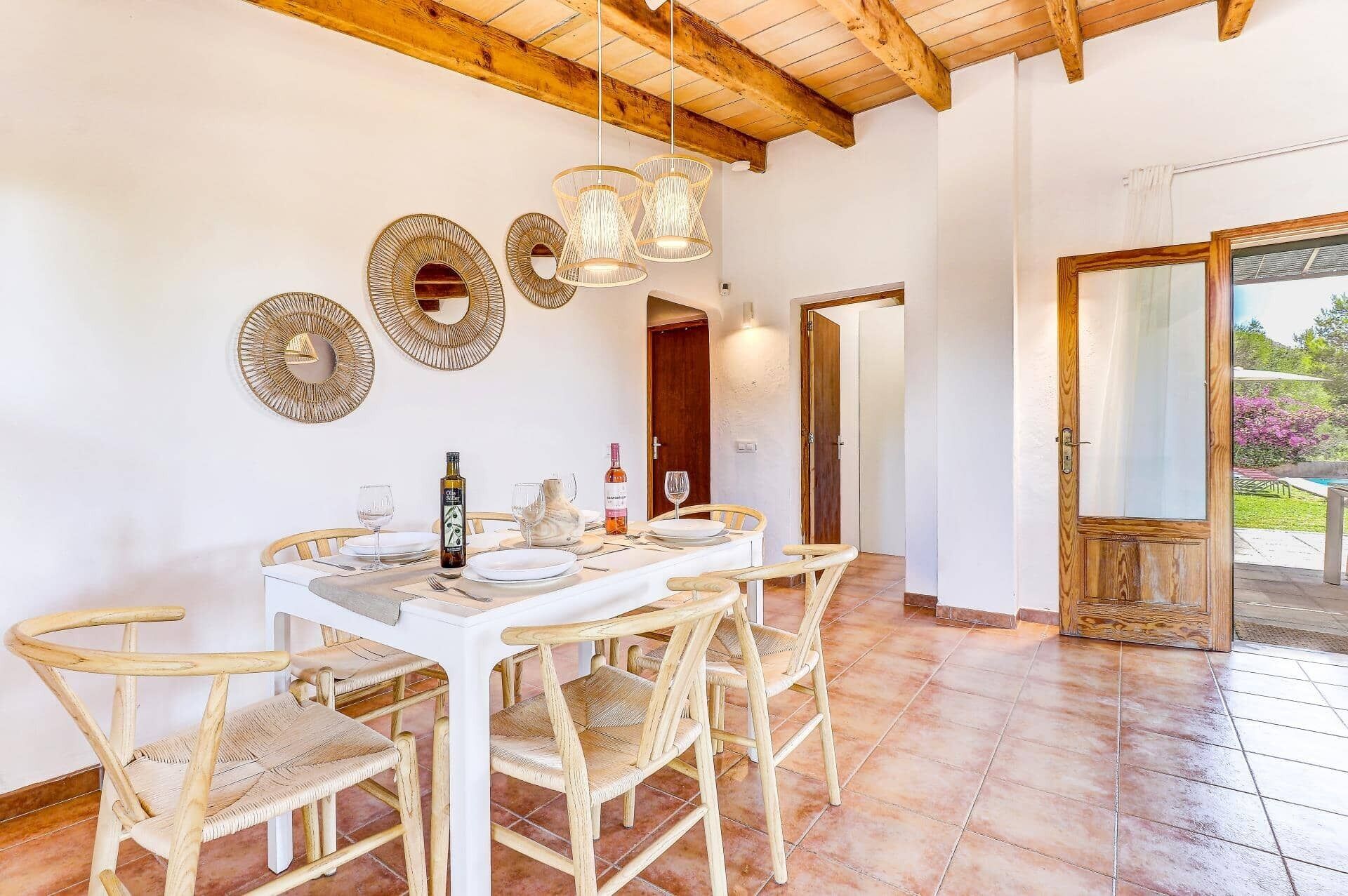 A dining area with a wooden table set for four, surrounded by wicker chairs.