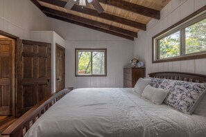 A bedroom with a wooden ceiling, a large bed with white bedding, a nightstand, and a window with a view of trees. - Raynor Shine Chalet by Innsbrook Vacations! (Innsbrook)