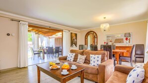 A living room with a sofa, coffee table, and dining area with chairs.