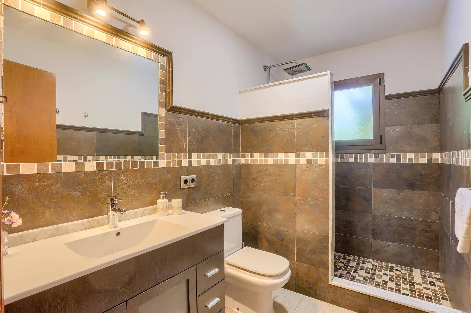 Une salle de bain équipée d’une douche, d’un lavabo, de toilettes et d’un miroir.