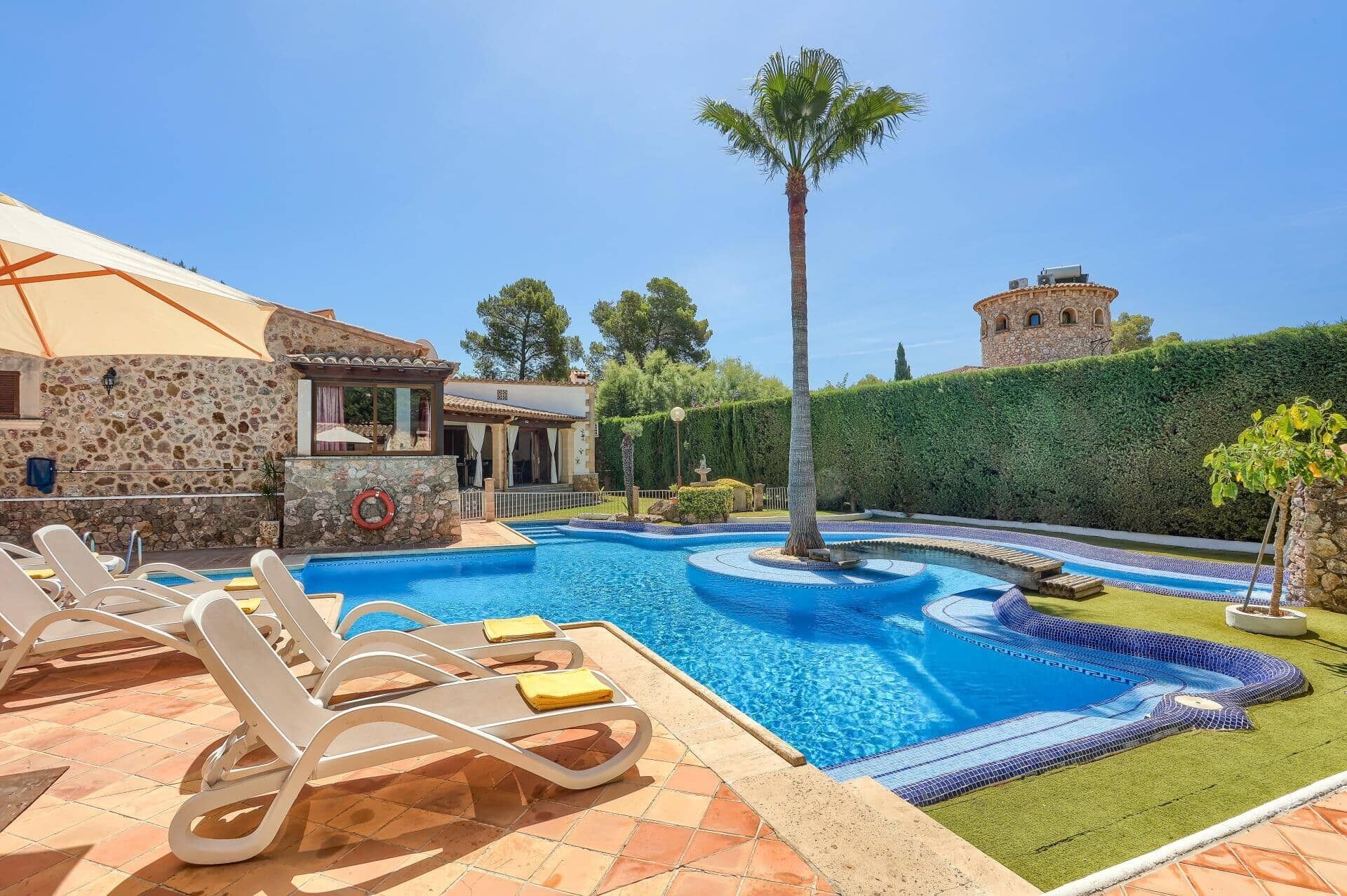 A swimming pool with lounge chairs, a stone building, and a tower in the background.