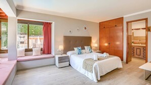 A bedroom with a bed, bedside tables, a window with curtains, a wooden wardrobe, and a bathroom with a mirror.