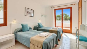 Camera d'albergo con due letti, una piccola scrivania, una sedia e un'ampia finestra vista esterna.
