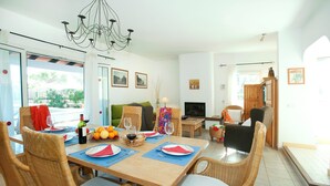 A dining area with wicker chairs, a wooden table set for four, and a chandelier. - Villa Reco by Villa Plus (Felanitx)