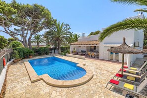 A swimming pool with a stone deck, surrounded by outdoor furniture and palm trees. - Villa Reco by Villa Plus (Felanitx)