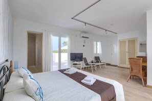 A hotel room with a bed, a TV, a desk, and a chair.
