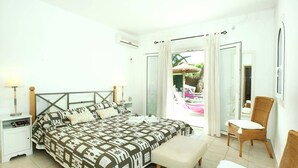 A bedroom with a bed, bedside tables, a chair, and a view of an outdoor area. - Villa Reco by Villa Plus (Felanitx)