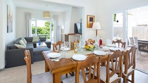 A dining area with a table set for four, a sofa, and a television in the background.