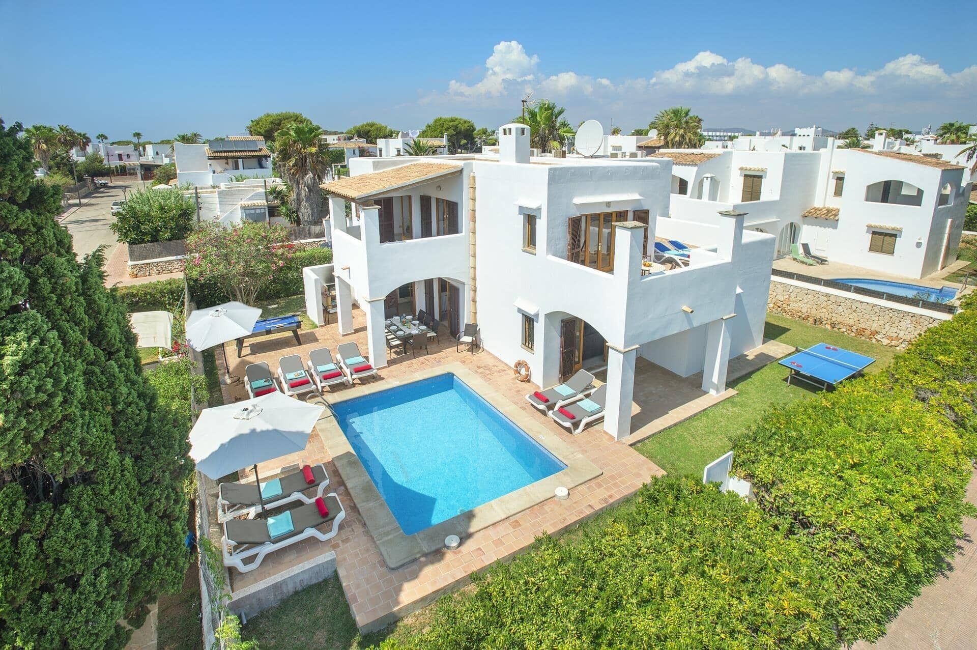 Eine moderne Villa mit Swimmingpool, Sitzgelegenheiten im Freien und Blick auf benachbarte Gebäude.