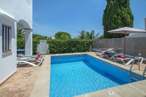 A swimming pool with lounge chairs and an umbrella, surrounded by a wooden fence and greenery. - Villa Roca Viva by Villa Plus (Cala d'Or)