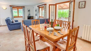 A dining area with a wooden table set for six, surrounded by wooden chairs. - Villa Garriguer by Villa Plus (Mallorca)