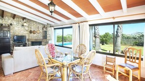 A spacious living area with a stone fireplace, a television, and a dining table with chairs. - Villa Francisca by Villa Plus (Mallorca)