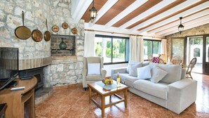 A living room with a stone fireplace, a sofa, and a television. - Villa Francisca by Villa Plus (Mallorca)