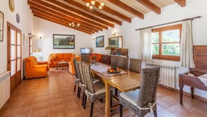 A dining area with a wooden table, patterned chairs, and a chandelier.