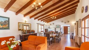 A spacious living area with a high ceiling, wooden beams, and a dining area with a table and chairs.