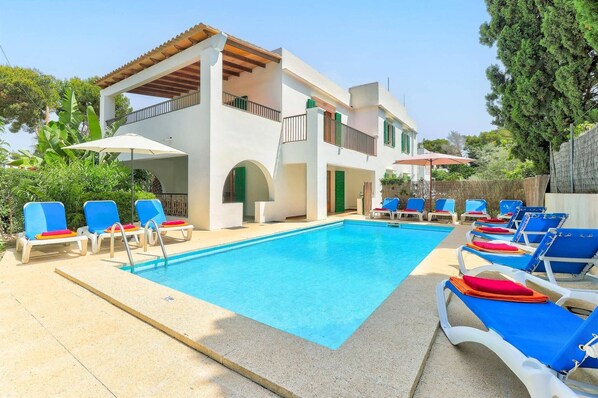 A poolside area with lounge chairs and a building with a balcony.