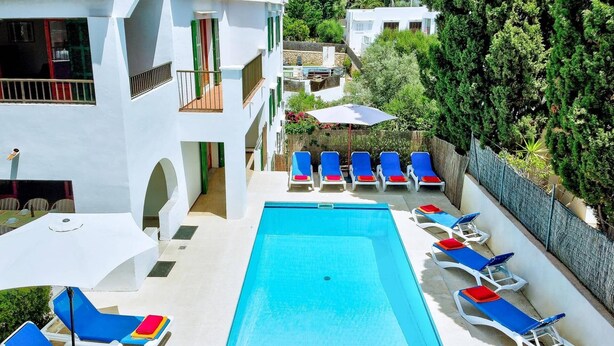 A pool area with multiple lounge chairs and a clear blue pool.