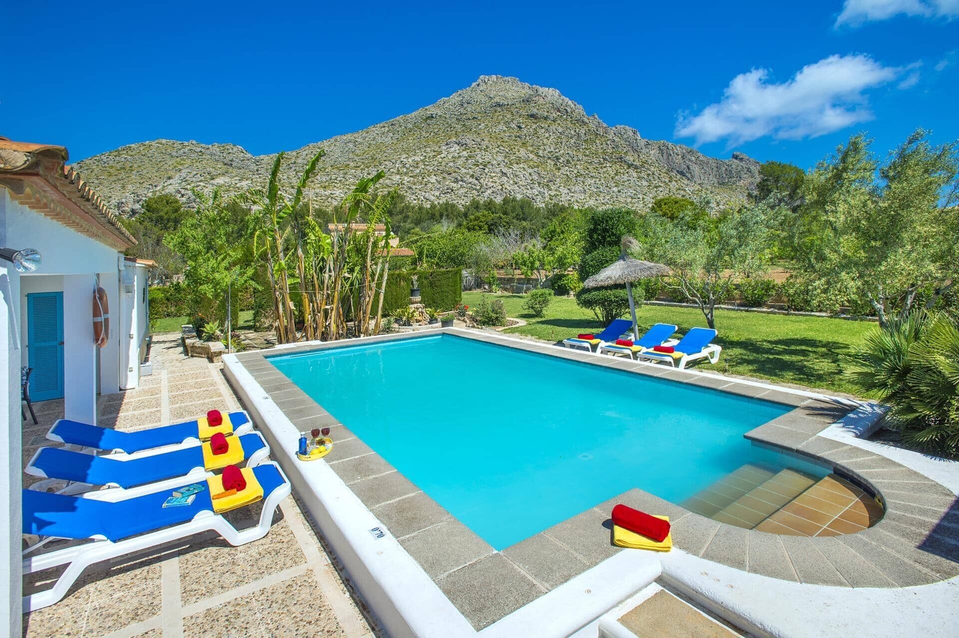A swimming pool with lounge chairs and a mountain in the background.