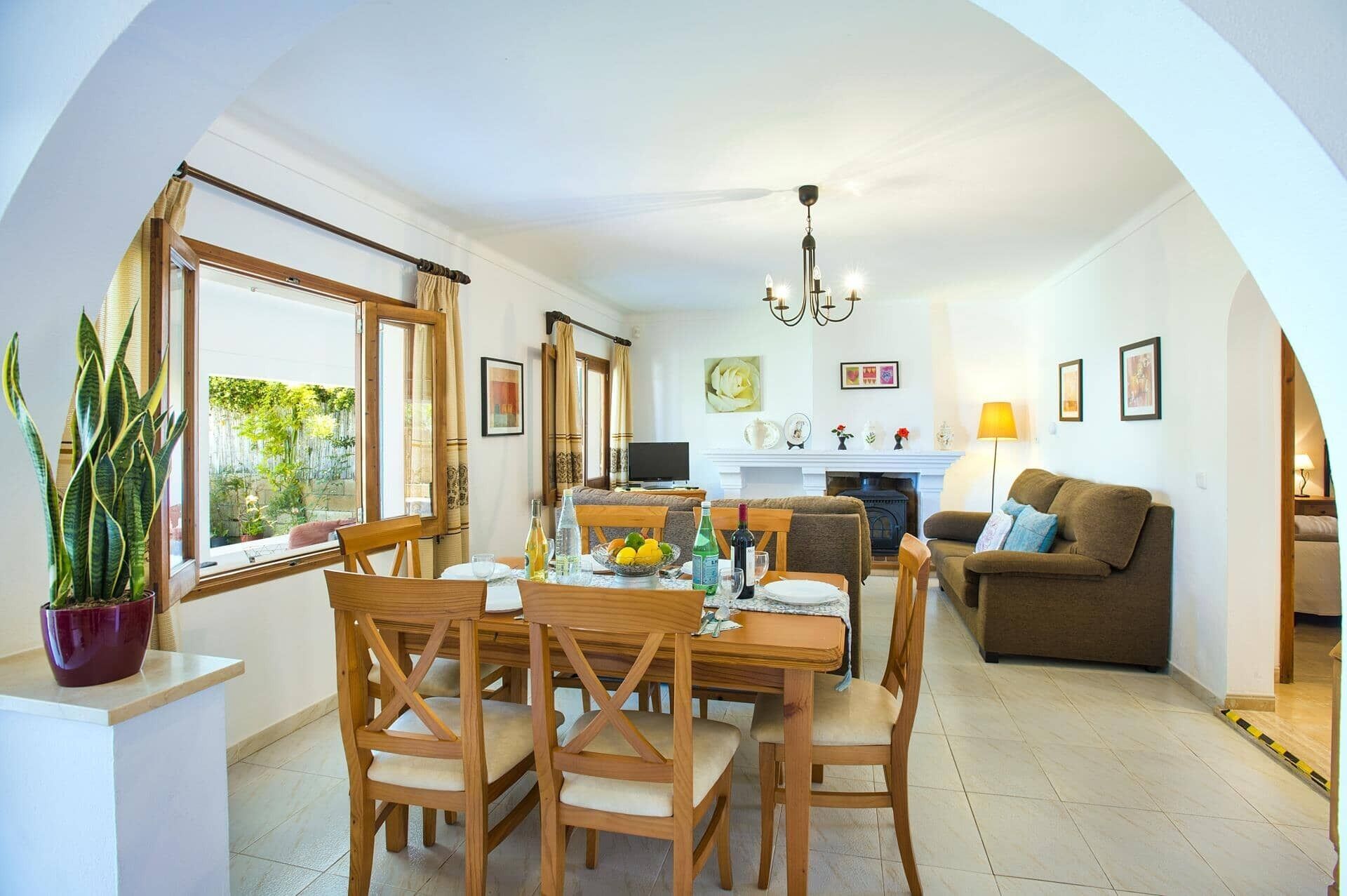 A dining area with a wooden table and chairs, a sofa, and a fireplace.