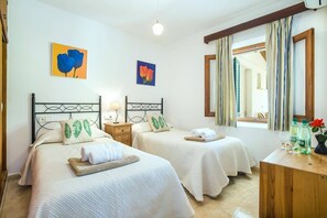 A hotel room with two beds, a wooden nightstand, a mirror, and artwork on the walls. - Villa Lorenzo by Villa Plus (Mallorca)